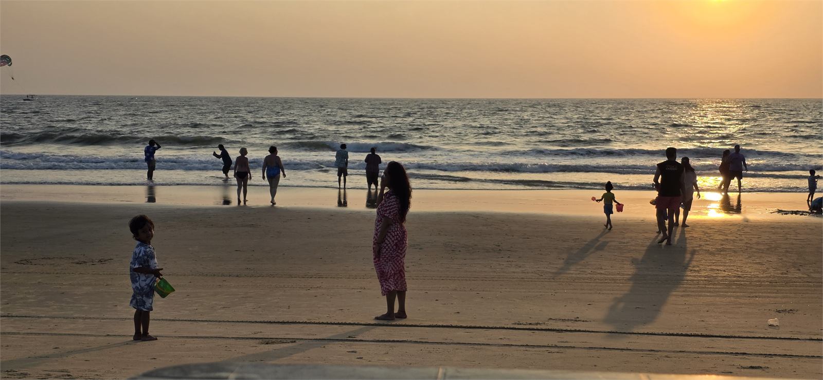 Sunset at a beach with people near the shoreline
